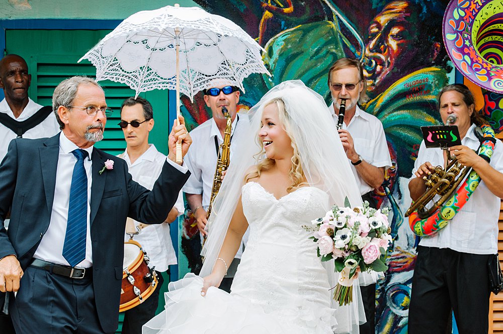 father of the bride holding an umbrella for the bride while a band performs at a Florida Keys wedding