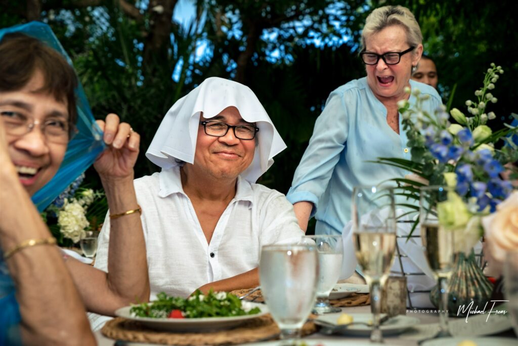 guests laughing at a wedding with napkins on their head due to hurricane season rain