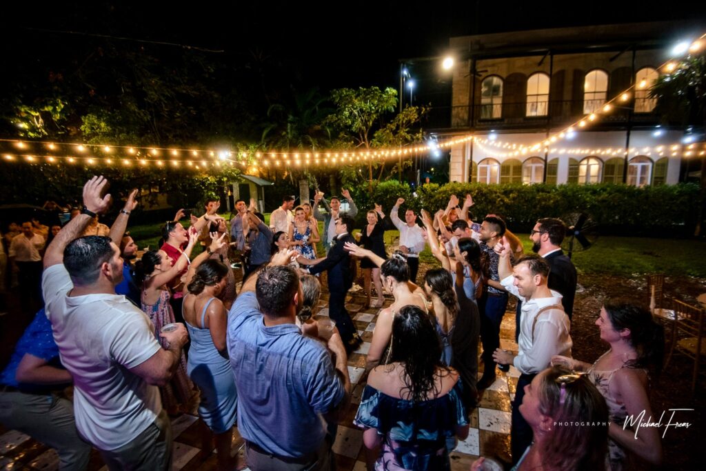 large bridal party dancing in the rain at the hemingway house in key west during hurricane season